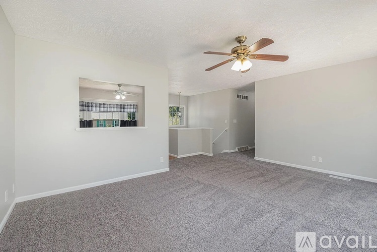 A spacious room with a ceiling fan and carpeted floor.