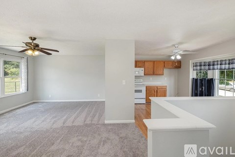 A spacious living room with a ceiling fan and a kitchen in the background.