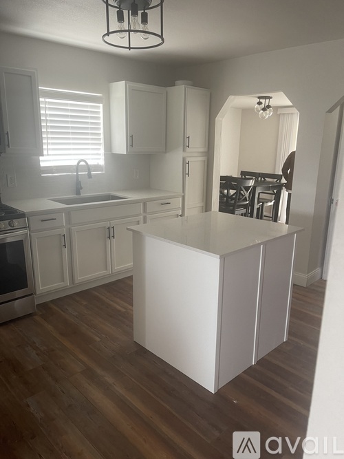 A kitchen with white cabinets and a wooden floor.
