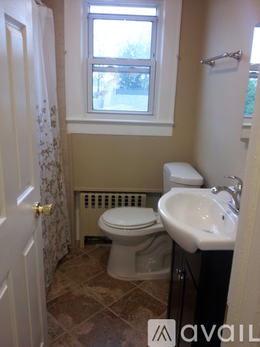 A bathroom with a toilet, sink, and window.