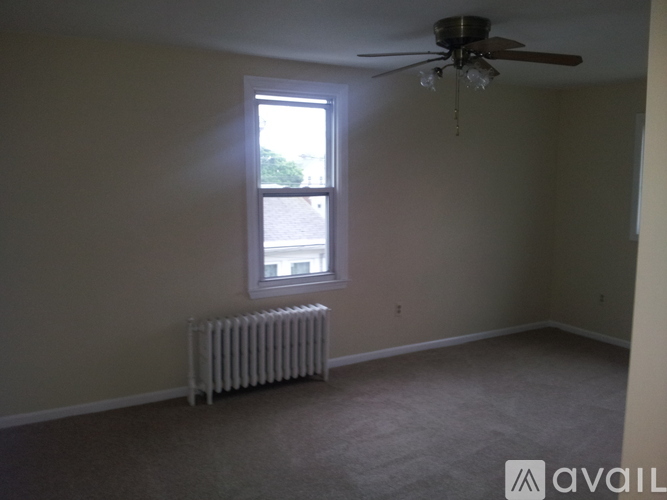 A room with a ceiling fan and a window with a view of a parking lot.
