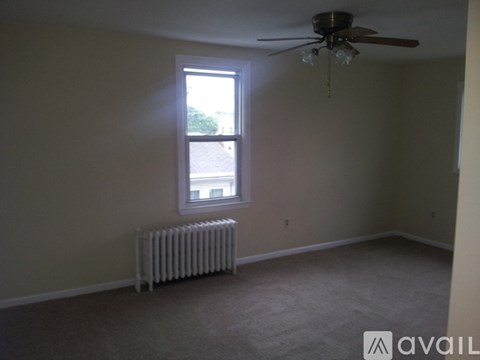 A room with a ceiling fan and a window with a view of a parking lot.