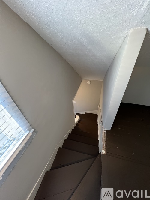 A staircase with a white wall and a window on the side.
