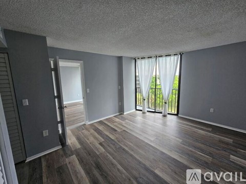 A room with wooden flooring and a sliding glass door leading to a balcony.