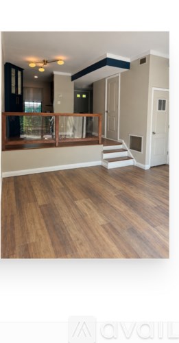A room with wooden floors and a staircase leading to another room.