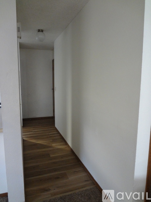 A hallway with a wooden floor and white walls.