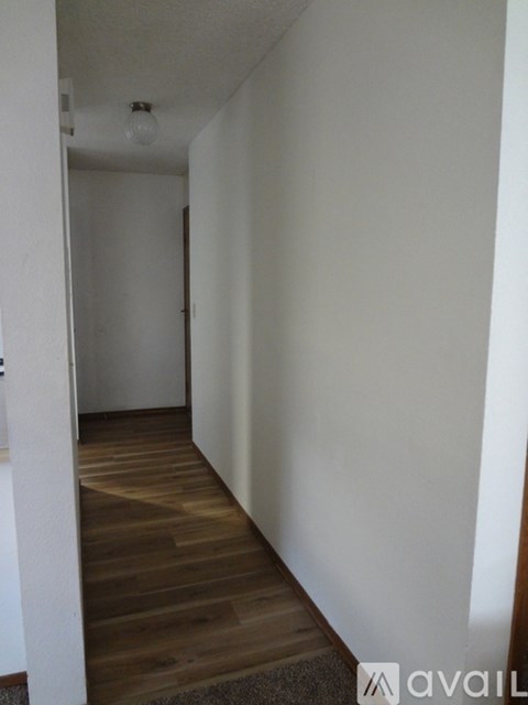 A hallway with a wooden floor and white walls.
