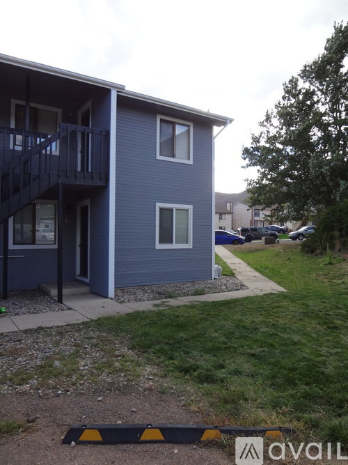 A blue house with a balcony and a tree in front.