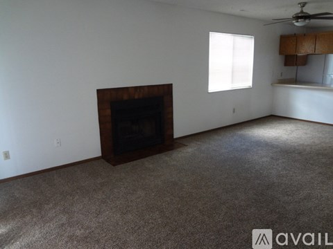 A living room with a fireplace and a ceiling fan.