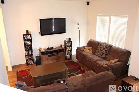 A living room with a brown couch and a television mounted on the wall.
