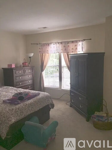 A bedroom with a bed, dresser, and window with curtains.