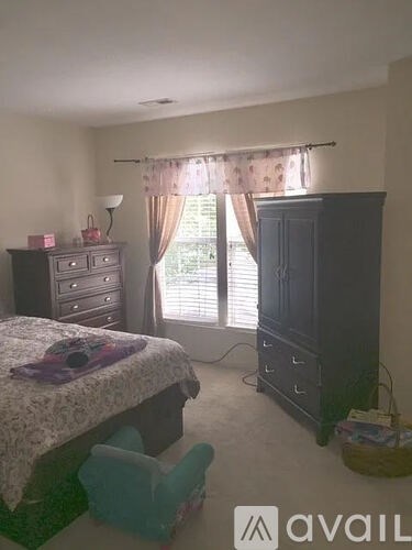 A bedroom with a bed, dresser, and window with curtains.