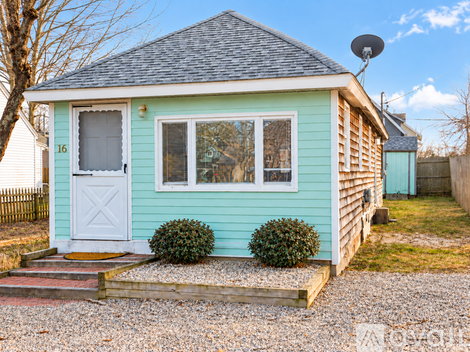 A small blue house with a white door and windows.