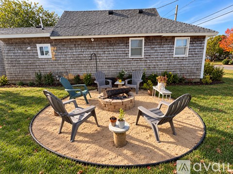 A backyard with a fire pit and chairs.