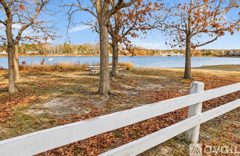 A white fence with a bench and trees in the background.