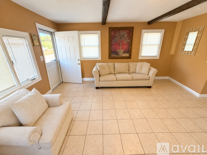 A living room with a white couch and a painting on the wall.