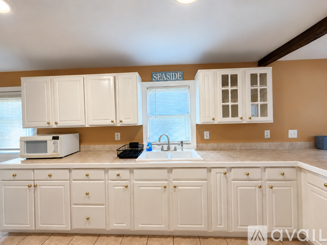 A kitchen with white cabinets and a sign that says "SEASIDE" on the wall.
