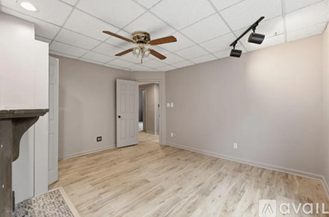 A room with a ceiling fan and a door in the background.
