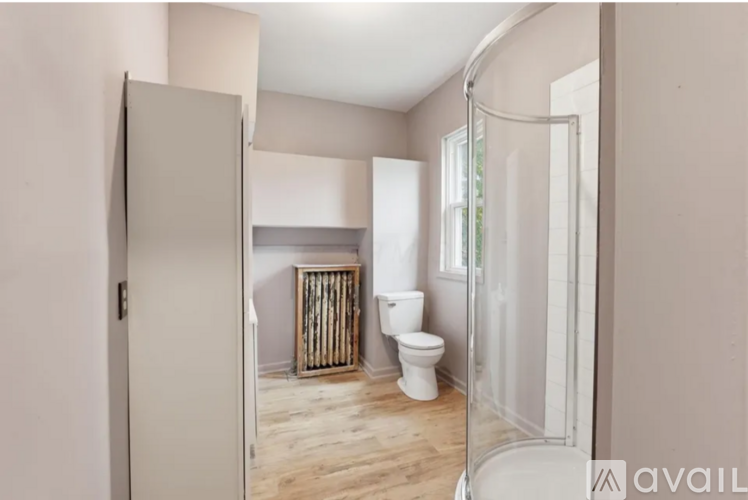 A bathroom with a toilet, a shower, and a wooden floor.