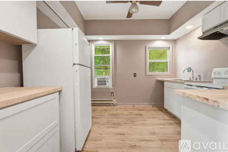 A kitchen with white cabinets and a window showing greenery outside.
