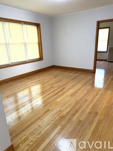 A room with wooden flooring and a window with blinds.