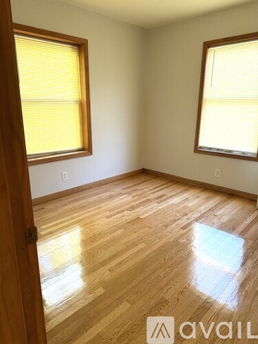 A room with wooden floors and two windows.