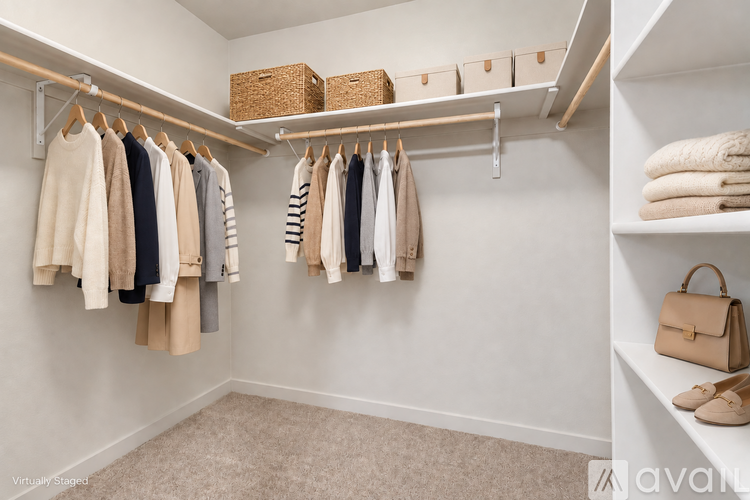 A white closet with clothes and a handbag on the shelf.