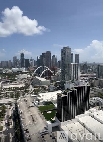 A cityscape with tall buildings and a large arch structure.