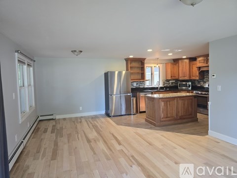 A kitchen with wooden floors and a stainless steel refrigerator.