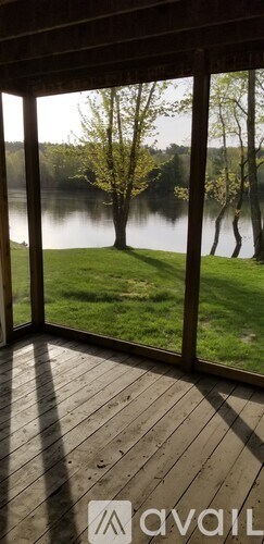 A view of a lake through a window with trees in the background.