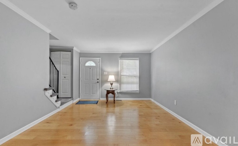 A spacious room with wooden floors and a staircase.