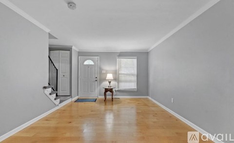 A spacious room with wooden floors and a staircase.