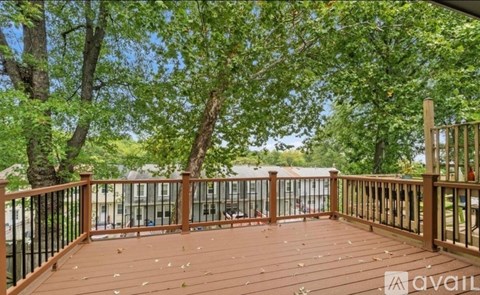 A wooden deck with a railing and trees in the background.