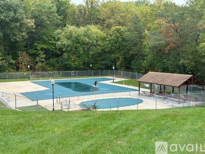 A pool surrounded by a fence with a small pavilion.