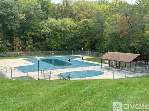 A pool surrounded by a fence with a small pavilion.