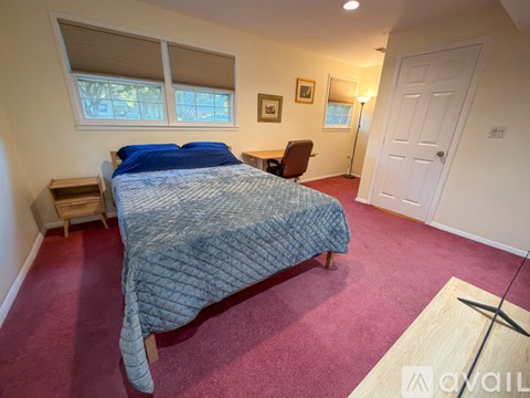 A bedroom with a bed, chair, and window.