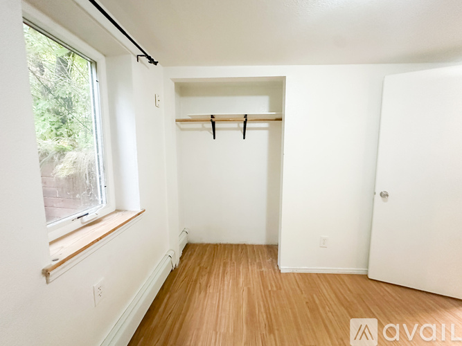 A room with a window and a wooden floor.