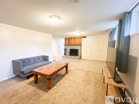 A living room with a grey couch, wooden coffee table, and a fireplace.