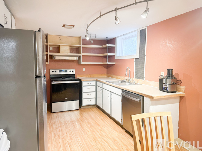 A kitchen with orange walls and a wooden floor.