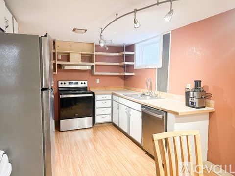 A kitchen with orange walls and a wooden floor.