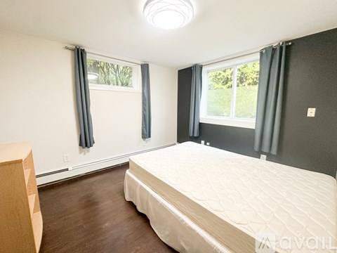 A bedroom with a large bed and a window with curtains.