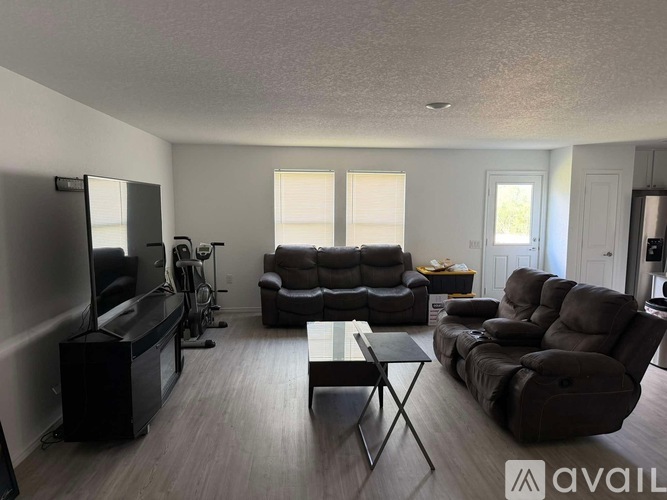 A living room with a television, two couches, a coffee table, and a television stand.