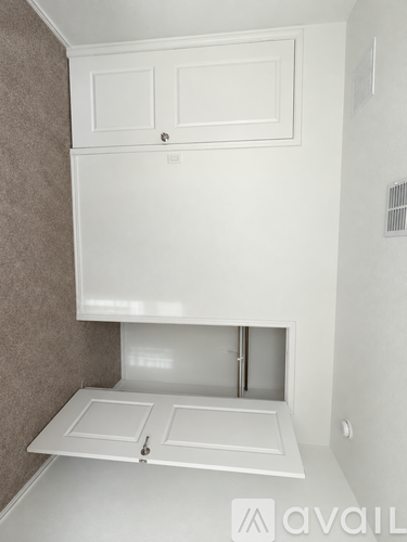 A white cabinet with a door and a drawer is mounted on a wall.