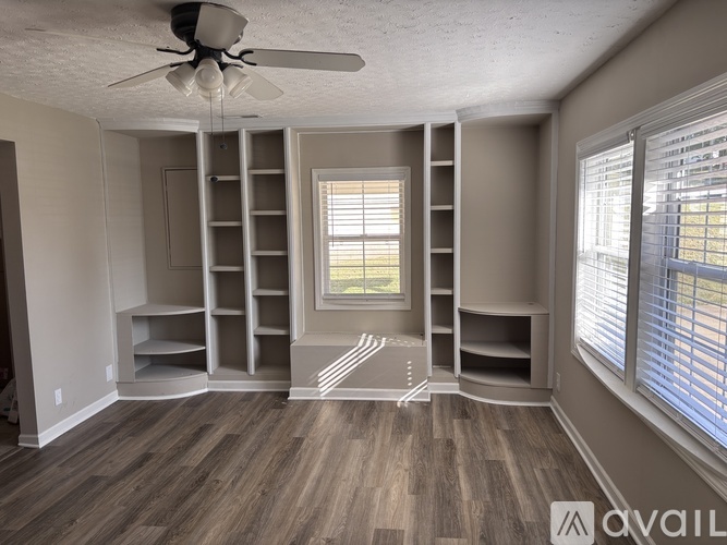 A room with a fan, shelves, and a window.