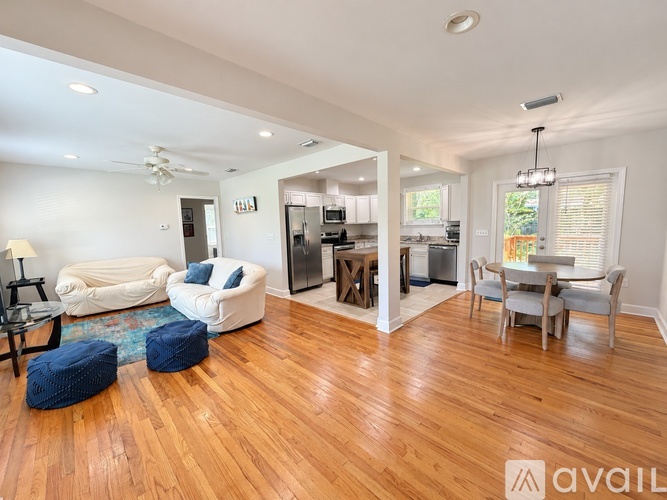 A living room with white furniture and a wooden floor.