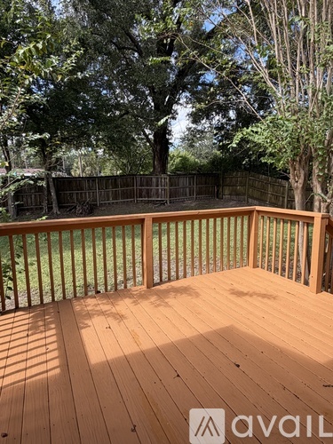 A wooden deck with a railing and trees in the background.