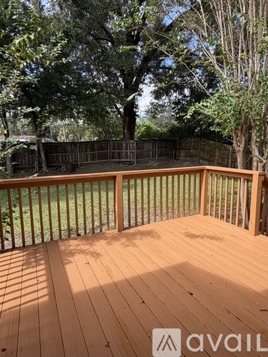 A wooden deck with a railing and trees in the background.