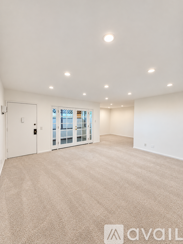 A spacious room with a carpeted floor and a door leading to a balcony.