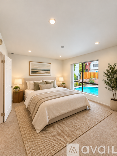 A bedroom with a large bed and a view of a pool outside the window.