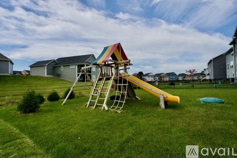 A playground with a slide and a swing set in a grassy area.